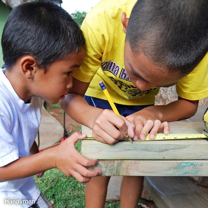 father and son use a tape measure on board