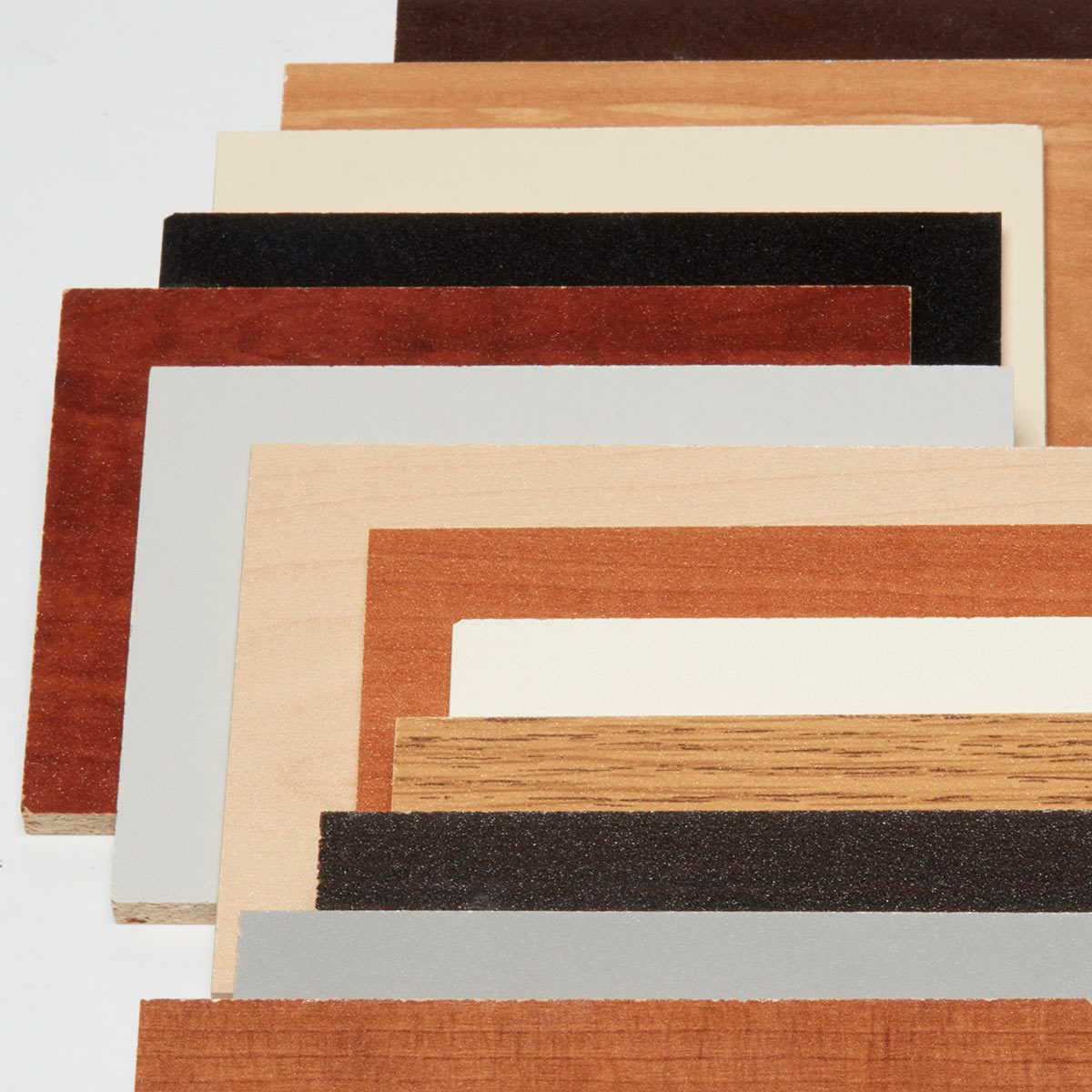 Various colored wood samples are arranged in layers. They display different textures and finishes, showcasing a range of wood tones against a neutral background.
