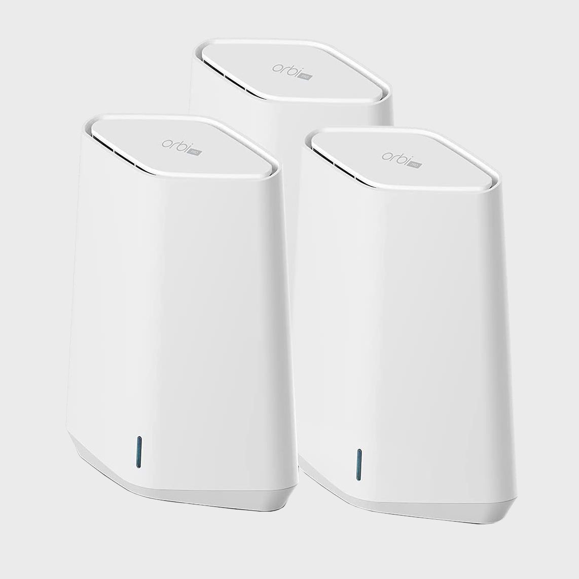 Three white wireless router units stand close together, designed for home networking, on a plain gray background.
