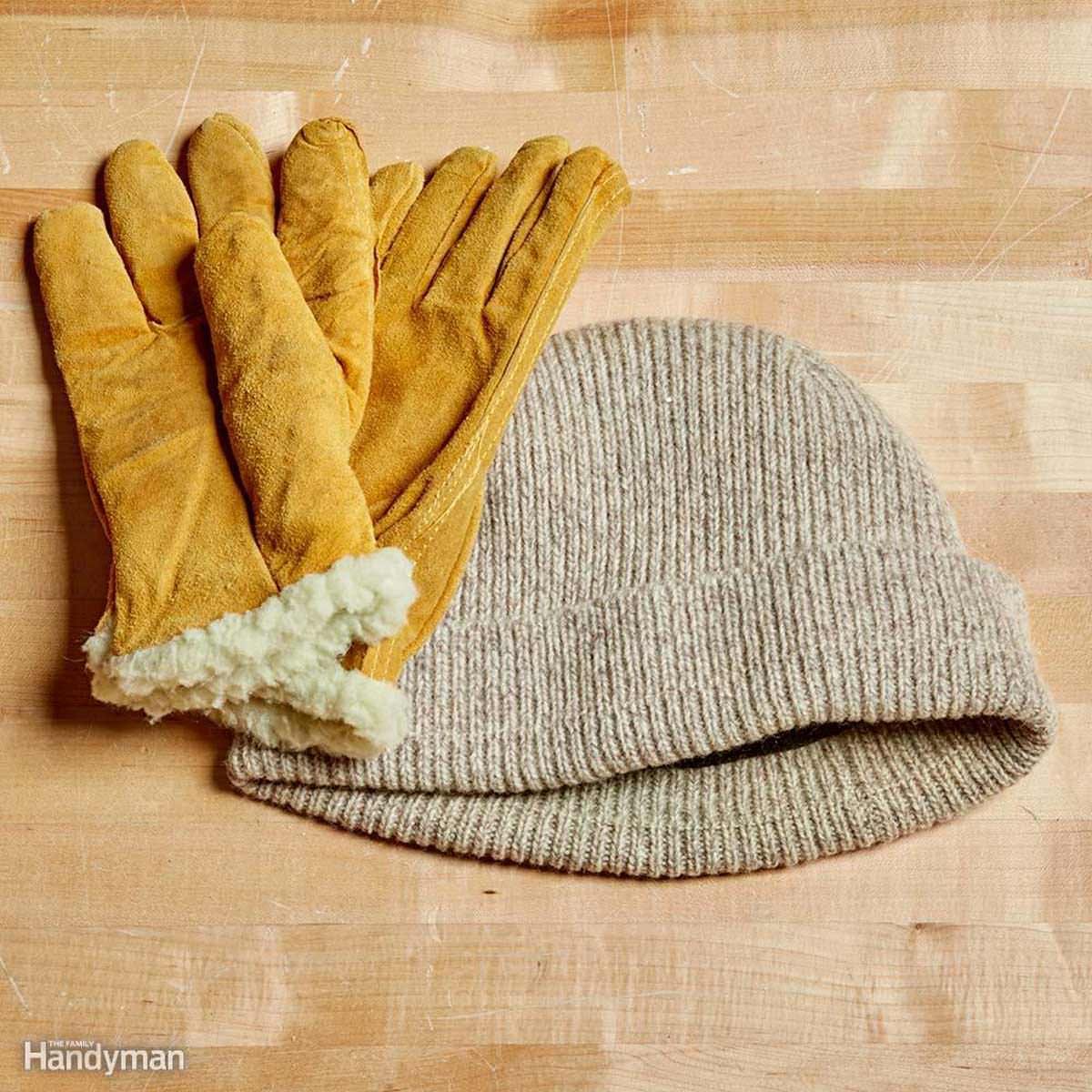 A pair of yellow gloves and a gray knitted beanie lie atop a textured wooden surface, suggesting readiness for cold weather activities.