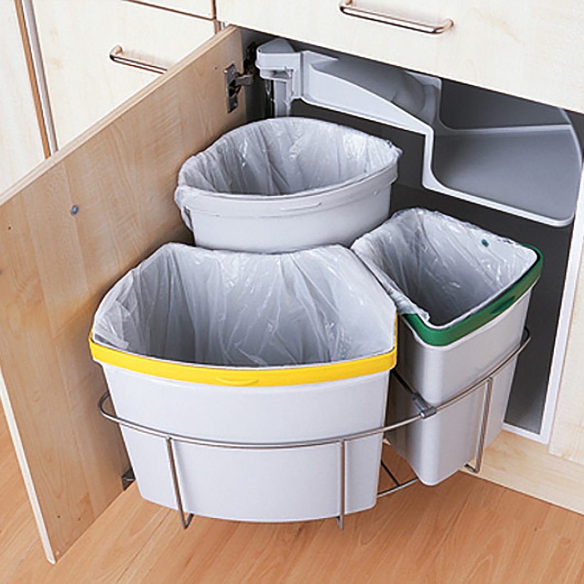 Three trash bins are mounted in a kitchen cabinet, with one gray bin featuring a yellow lid, another gray with a green lid, and one more gray bin.