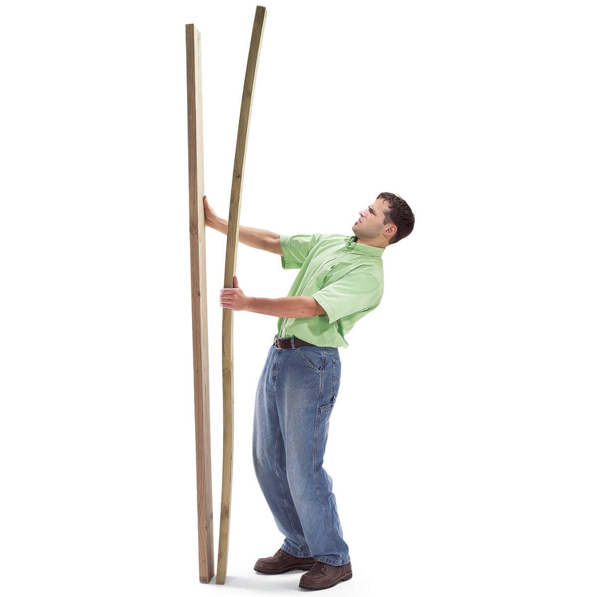 A man in a green shirt leans against two wooden planks, pushing them slightly apart in a bright, plain background.