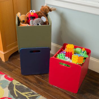 Two storage bins hold toys: one green with plush animals peeking out, and one red filled with colorful building blocks. A rug lays beneath.