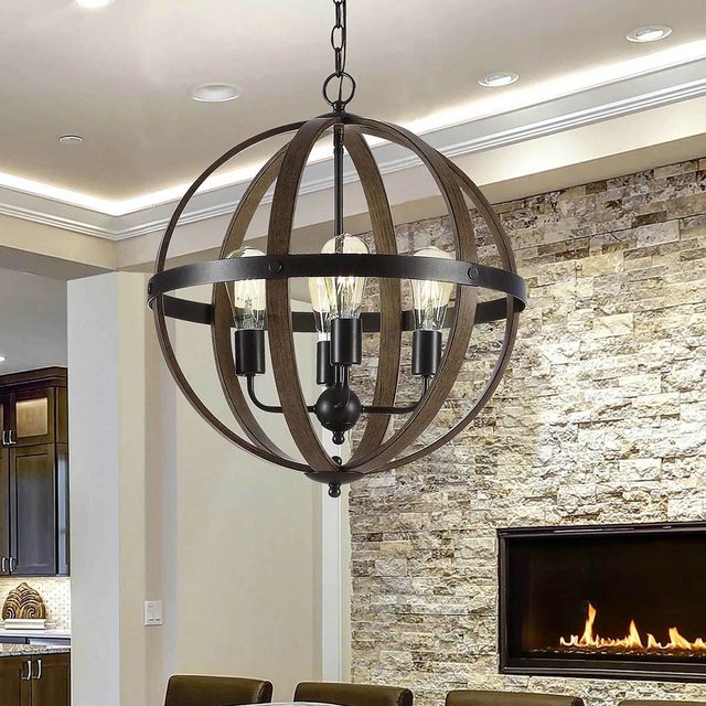 A spherical chandelier hangs from the ceiling, illuminating a stone wall and a modern fireplace in a stylish interior space.