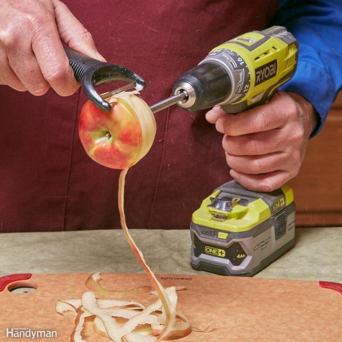 A person uses a drill to peel an apple, with long peels falling onto a cutting board beside sliced apple skins, in a kitchen setting.