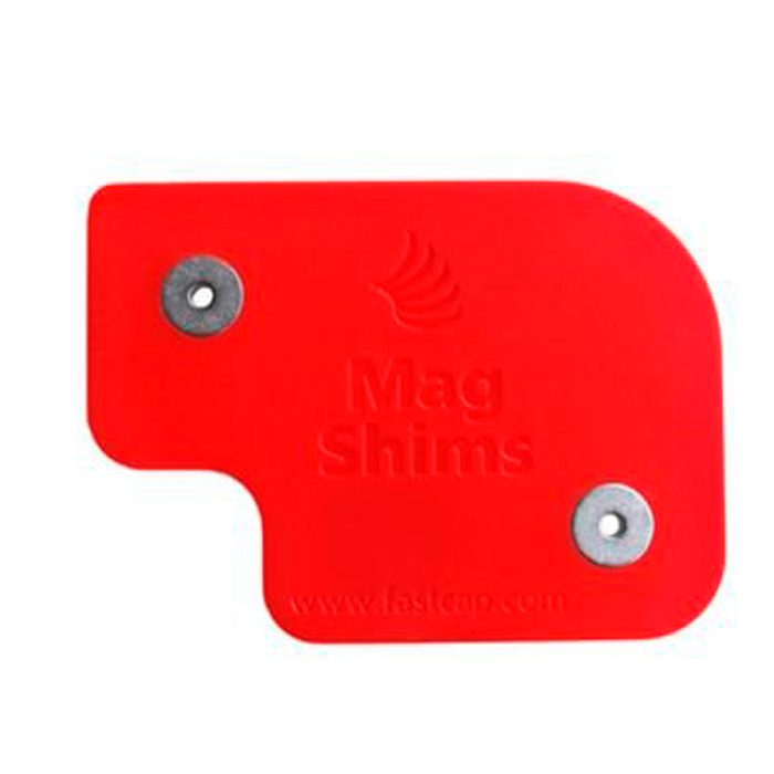 A red plastic shim with two metal discs, used for adjusting measurements in construction or woodworking, rests on a neutral background.