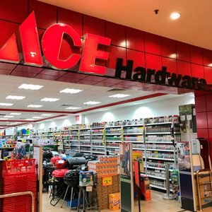 An ACE Hardware store displays shelves filled with various products, while shoppers navigate aisles among grills and promotional items in a bright, open layout.