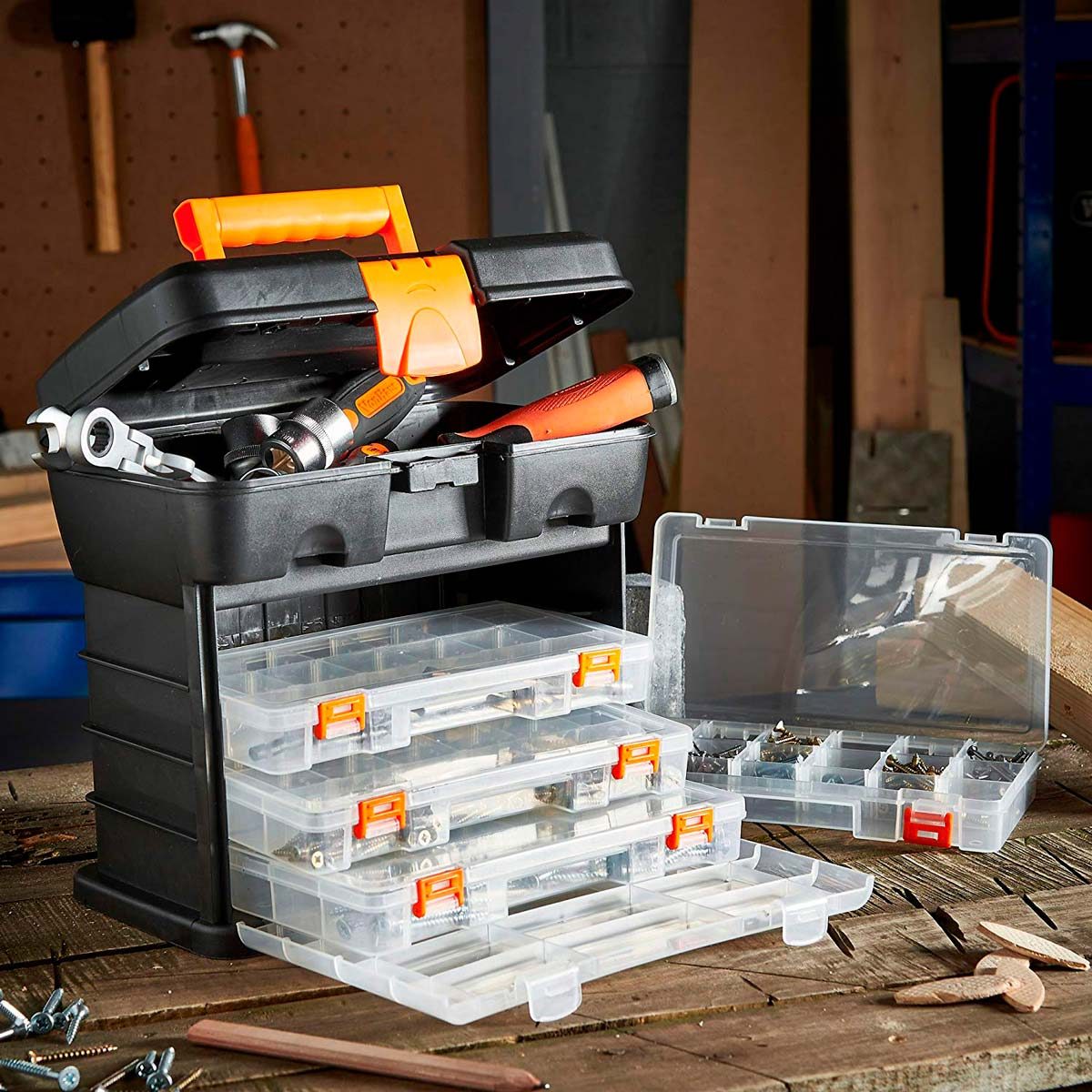 A black toolbox with orange accents holds various tools, while transparent containers filled with screws rest beside it on a wooden workbench.