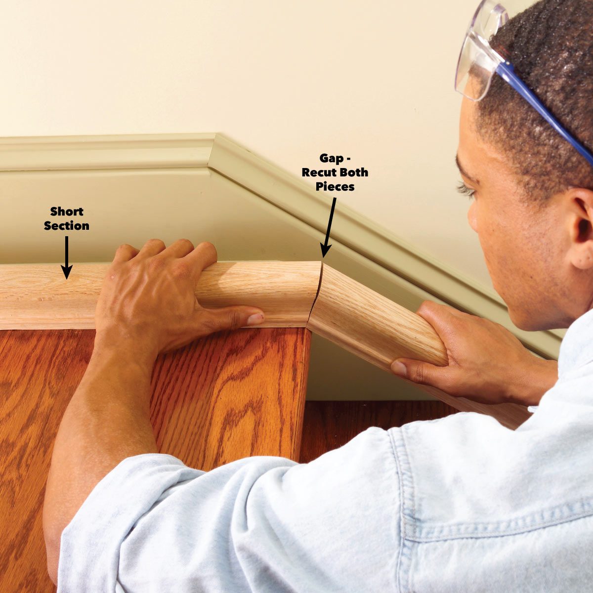 A person adjusts a wooden handrail piece, aligning it to eliminate a gap. The setting is an interior room with wooden flooring and wall trim.