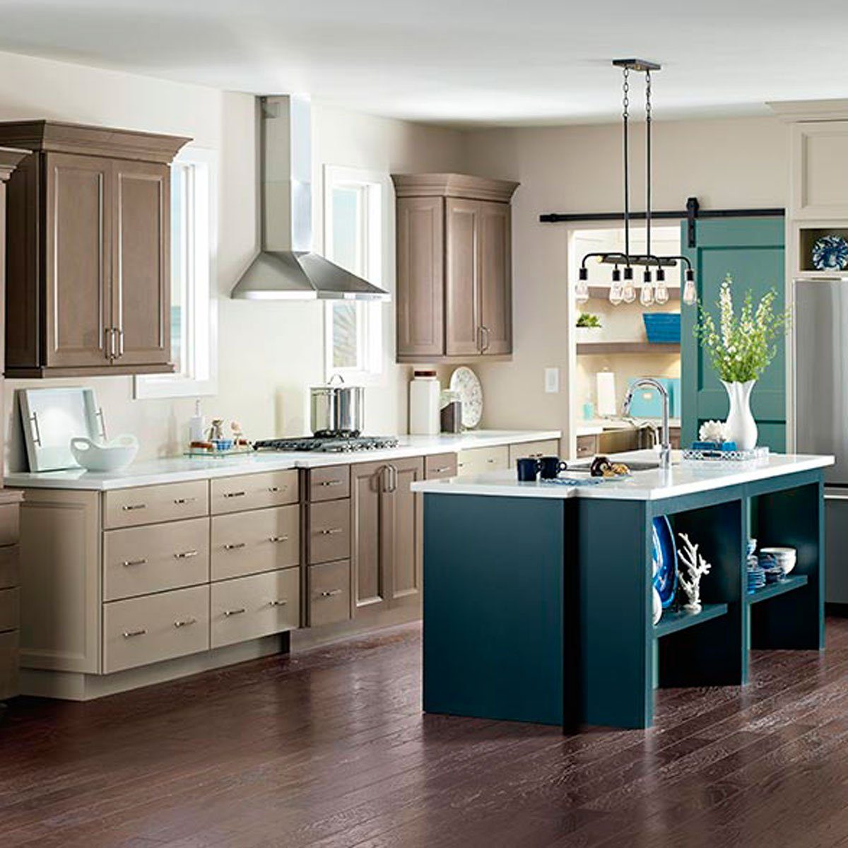 A modern kitchen features wooden cabinets, a center island, and stainless steel appliances, illuminated by pendant lights, creating a bright and inviting atmosphere.