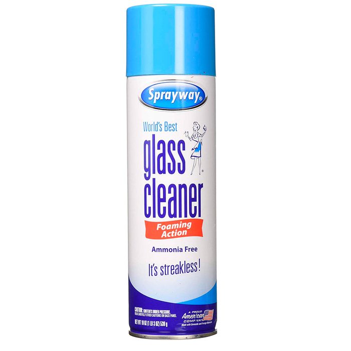 A cylindrical can of glass cleaner rests upright. It features a bright blue cap and labels promoting its foaming action and ammonia-free formula.