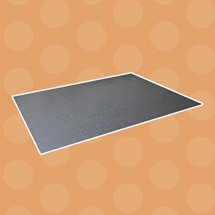 A rectangular, textured mat lies flat on a light orange background with circular patterns, suggesting a simple decorative or functional surface.