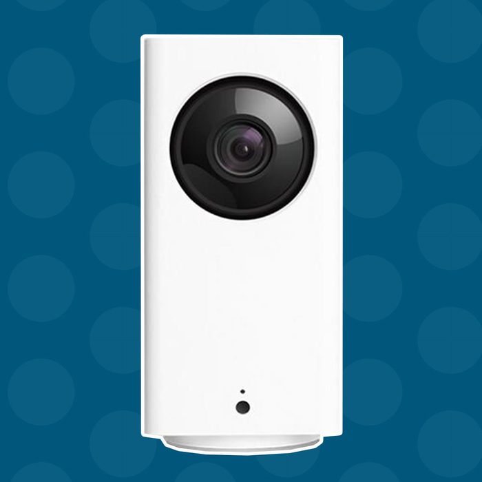 A white security camera stands upright, capturing images. It is set against a blue background with circular patterns, indicating a modern, tech-friendly environment.
