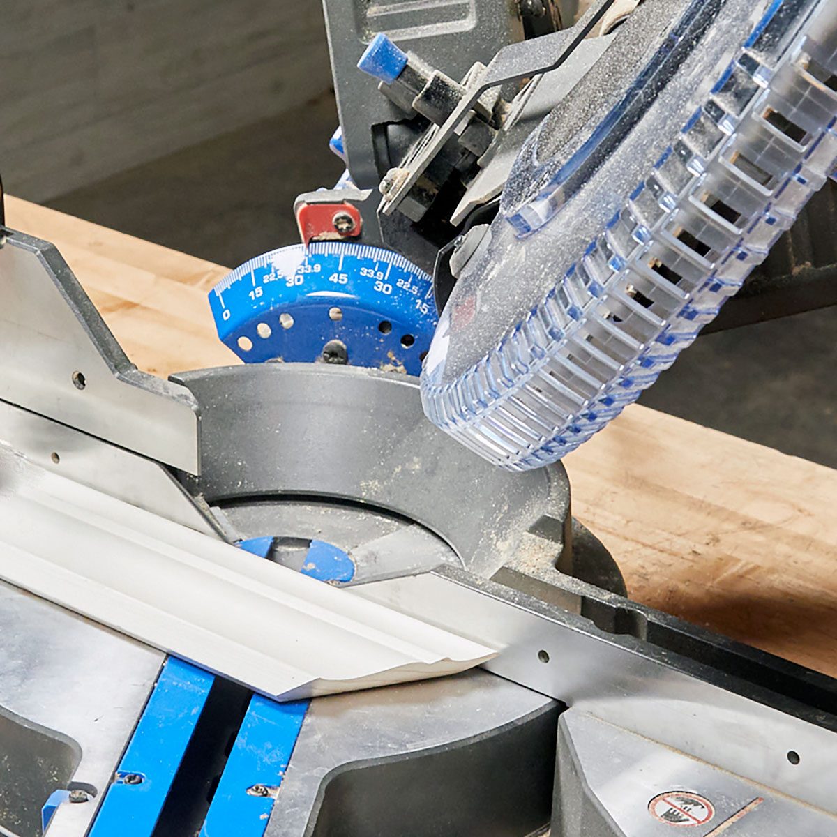 A piece of crown molding laid flat on a miter saw | Construction Pro Tips