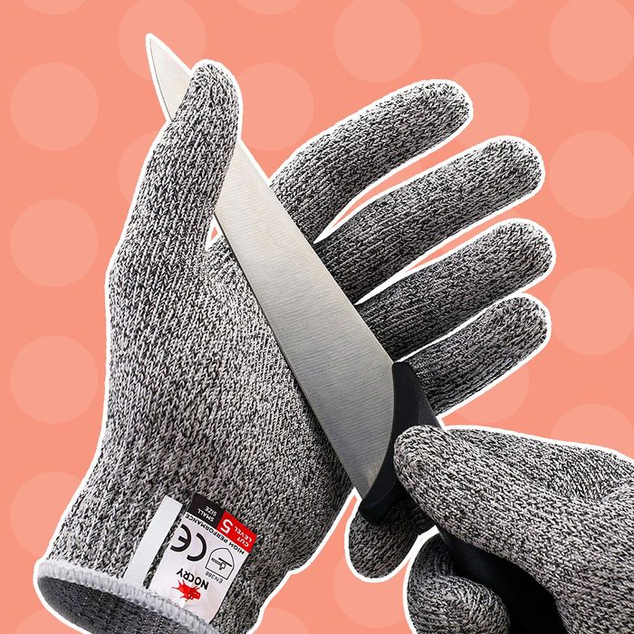 A hand wearing a protective glove holds a kitchen knife, positioned at an angle, against a textured background with soft circles.