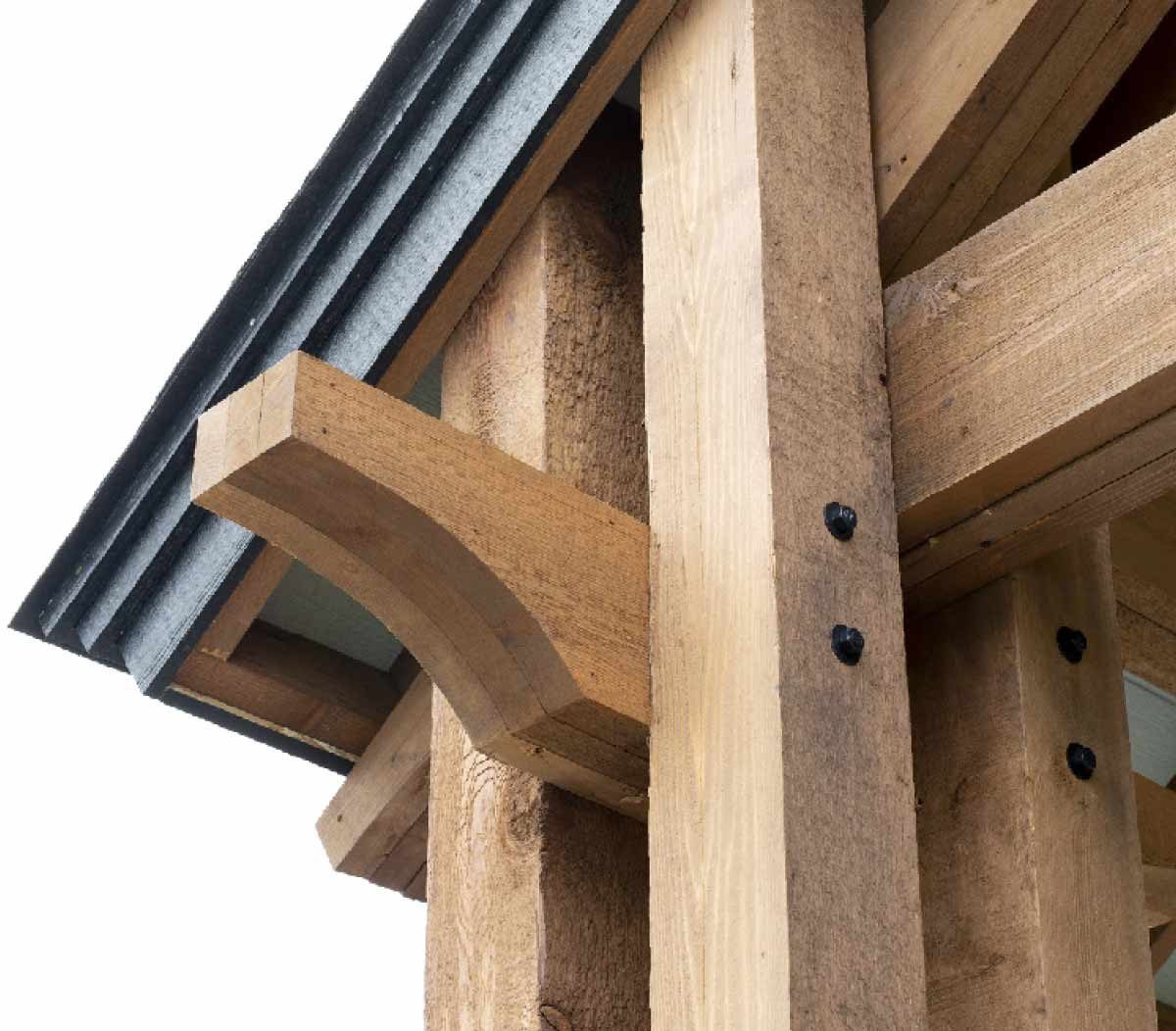 A wooden support beam with a rounded end connects to a structure, partially covered by a slanted metal roof, showcasing rustic architecture.