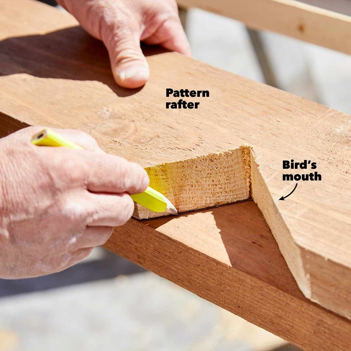 A hand holds a yellow pencil, marking a wooden rafter with a cut labeled “Bird’s mouth,” on a construction surface.
