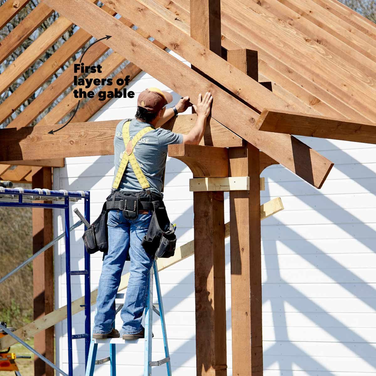 A construction worker on a ladder frames the wooden gable of a building, using tools in a sunny outdoor environment.