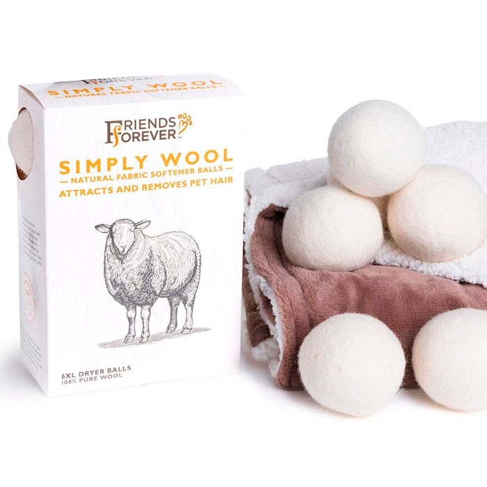 A box of wool dryer balls sits beside folded, textured towels. The balls are white and fluffy, designed to attract and remove pet hair.