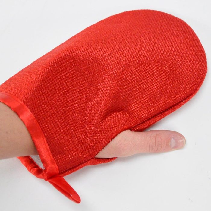 A hand is partially covered by a red oven mitt, designed to protect against heat in a kitchen setting. The background is plain and light-colored.