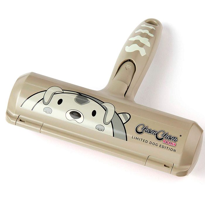 A pet hair roller with a light beige handle, featuring a cartoon dog design, is designed for removing hair from various surfaces.