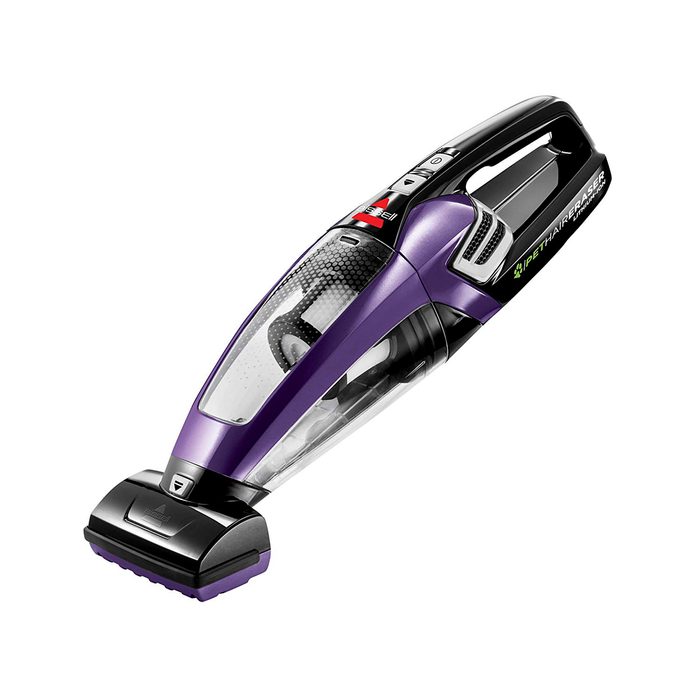 A purple handheld vacuum cleaner is positioned at an angle, designed for cleaning pet hair, featuring a transparent dust container and various controls on top.