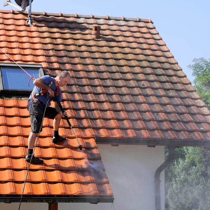 Man-pressure-washes-roof