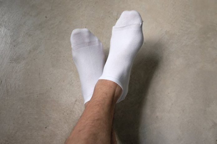 Man wearing socks crossing his legs. He is resting and moving his legs up