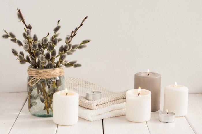 Flowers composition. White candles and willow branches on white wooden background. Spa