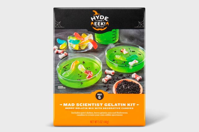 Colorful gelatin cups with gummy worms and decorative candies are displayed on a dark surface, suggesting a fun, Halloween-themed treat-making kit.