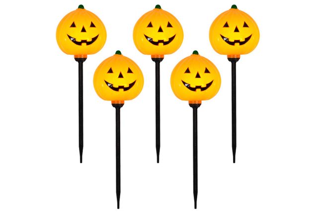 Five glowing pumpkin decorations, featuring cheerful faces, are positioned upright on black stakes, suitable for outdoor Halloween decoration.