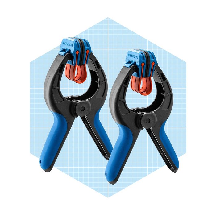 Two clamping tools are positioned side by side, each with black bodies and blue handles, set against a light blue grid-patterned background.