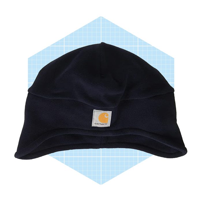 A dark blue fleece hat lies flat, featuring a small logo patch, set against a light blue grid background.