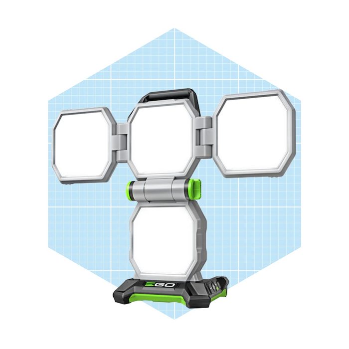 A portable light with three adjustable panels is positioned upright on a base, set against a light blue grid background.