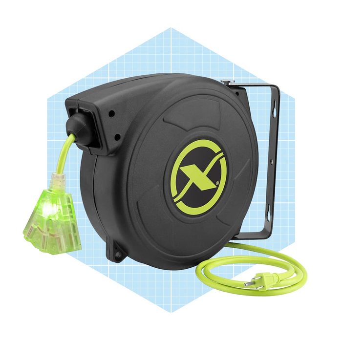 A retractable extension cord reel is mounted, with a bright green cord extended and glowing plug, set against a light blue grid background.