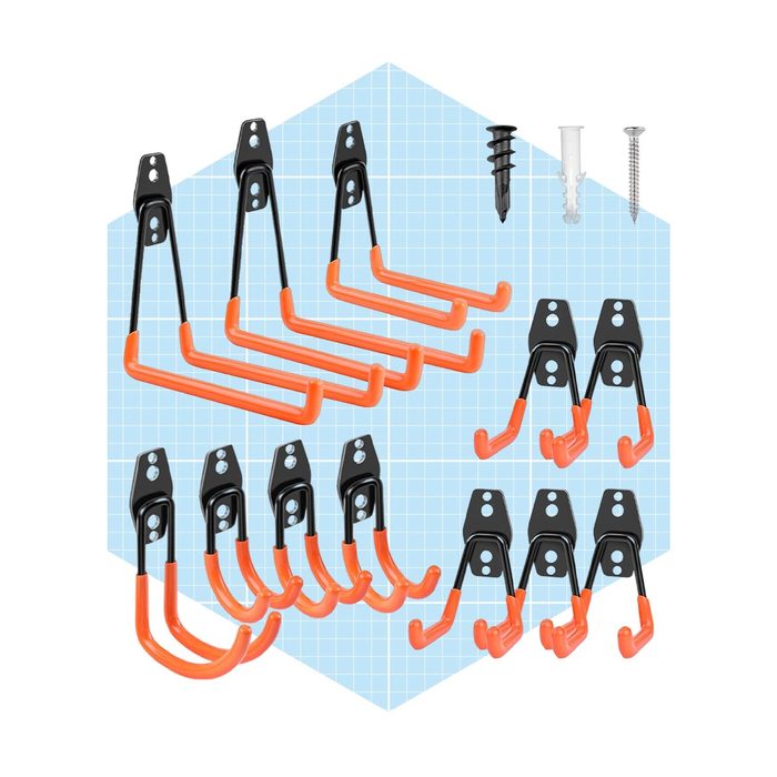A set of metal hooks with orange rubber grips is arranged on a light blue grid background, accompanied by screws and wall anchors for installation.