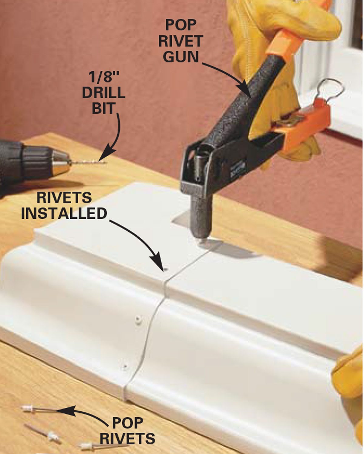 A pop rivet gun applies rivets to a white metal seam on a wooden surface, with tools including a drill bit and rivets nearby.