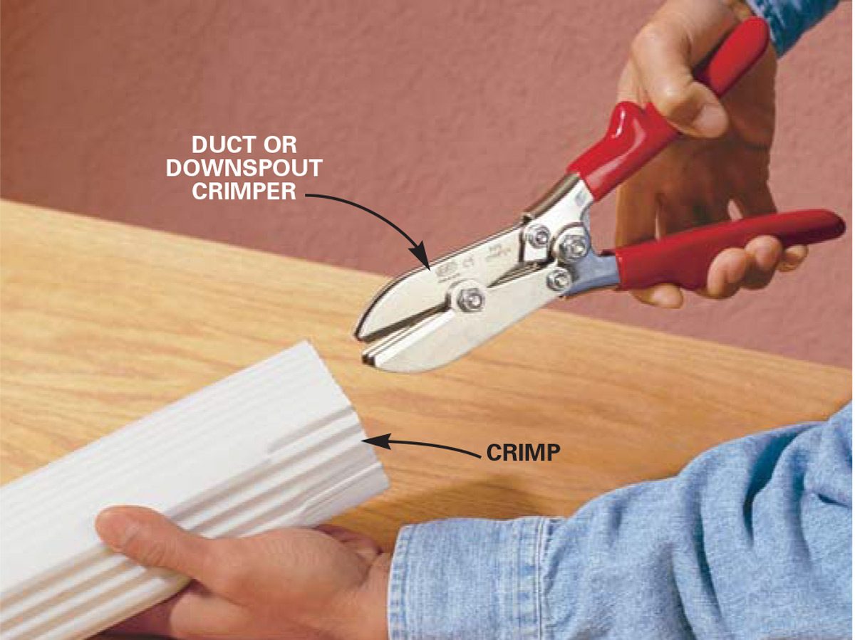 A person uses a crimper on a white material to create a crimp, with a wooden surface and a pink wall in the background.
