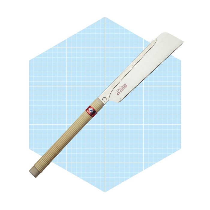 A hand saw with a curved blade rests diagonally on a light blue grid-patterned background, showcasing its sleek design and wooden handle.
