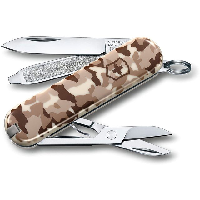 A multi-tool with a camo design features a knife blade, scissors, and a file, showcasing its functionality for outdoor or maintenance tasks.