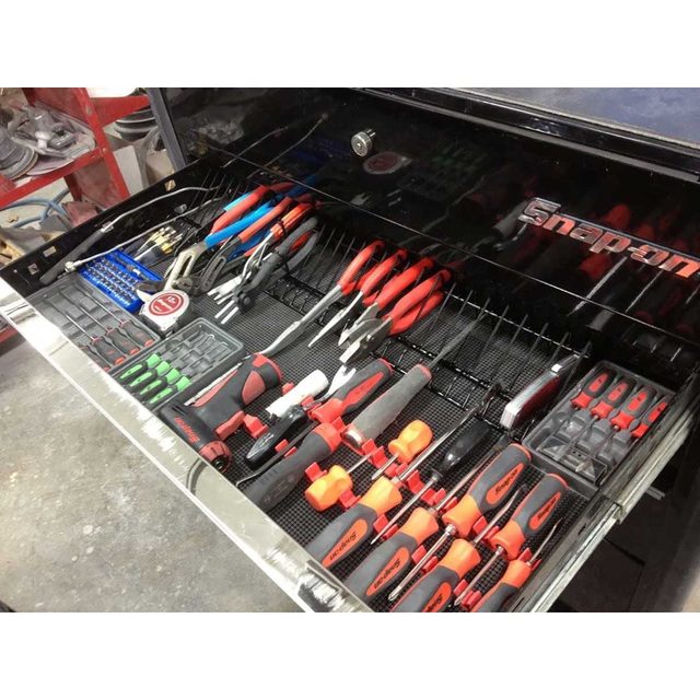 A toolbox drawer contains neatly organized tools, including pliers, screwdrivers, and wrenches, set against a dark background, showing meticulous arrangement.