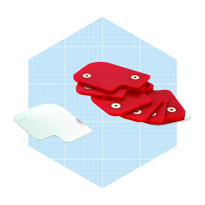 A stack of red silicone spatulas and a metal spatula rest on a light blue grid background, ready for use in cooking or baking tasks.