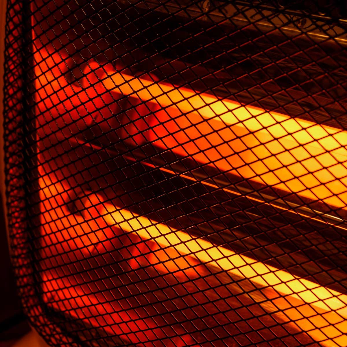 A heat lamp emits warm, glowing light through a mesh grille, casting an orange hue in a dimly lit environment.