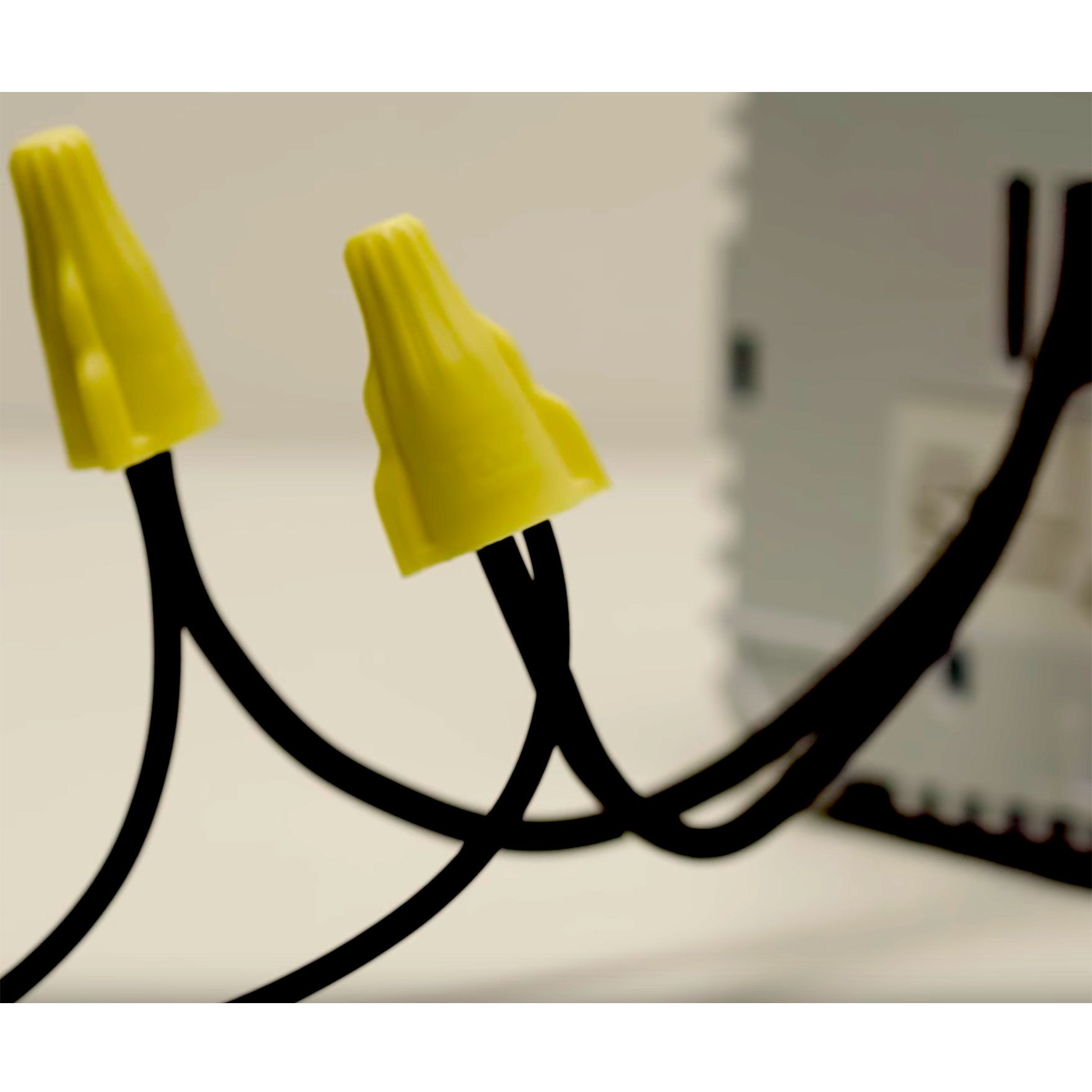 Two yellow wire connectors sit atop black wires leading to a device in a neutral, well-lit environment, suggesting electrical work or connections.