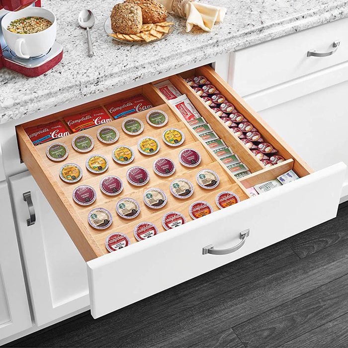 A kitchen drawer displays various coffee pods and soup cans, organized neatly with baked goods placed on the countertop, emphasizing a functional kitchen space.