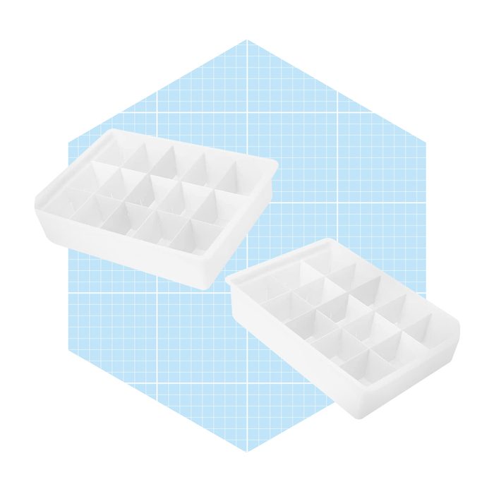 Two white ice trays with multiple compartments are positioned against a light blue grid background. They are designed for making uniquely shaped ice pieces.