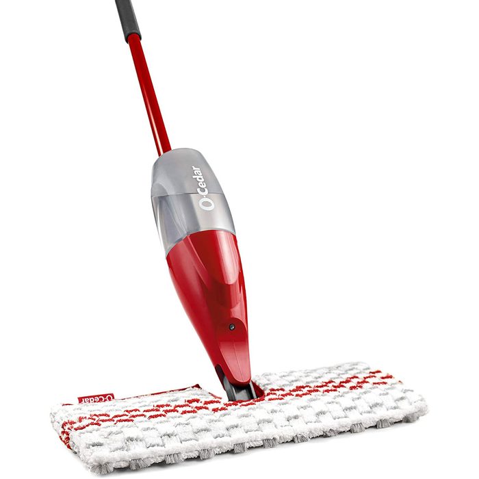 A red and gray mop stands upright, featuring a textured cleaning pad, poised for use on a flat surface, ready for cleaning tasks.