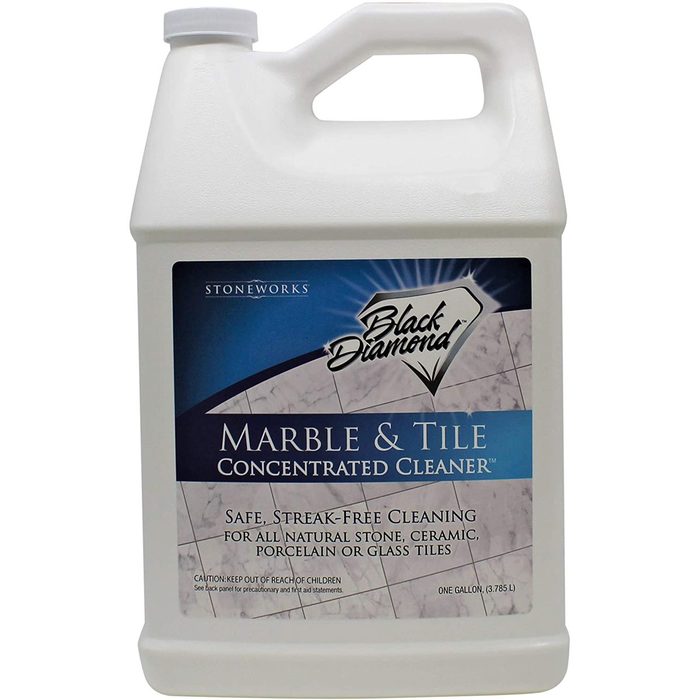 A large plastic jug of concentrated cleaner is labeled for use on marble and tile, promoting safe, streak-free cleaning for various surfaces.