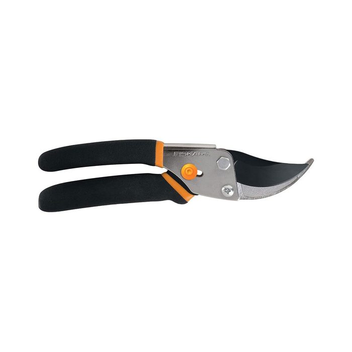 A pair of garden shears are positioned flat, with a curved metal blade and rubberized handles, ready for cutting branches in a gardening context.