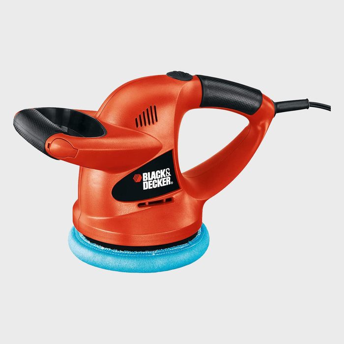 A red electric hand sander is positioned upright, ready for use, featuring a blue sanding pad. It is set against a plain white background.